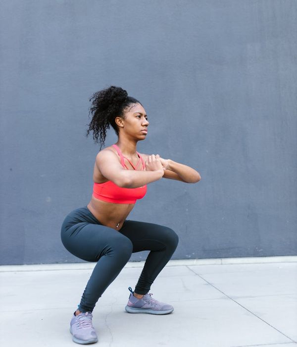 A fit person performing dynamic strength movements in a dark minimalist gym environment